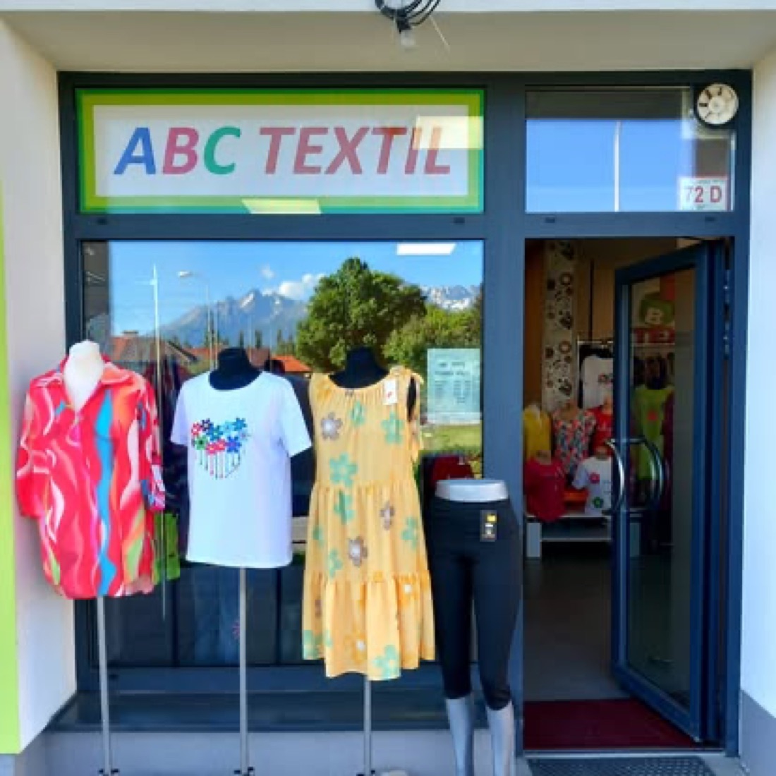 Predajňa ABC Textil s figurínami a Vysokými Tatrami v pozadí
